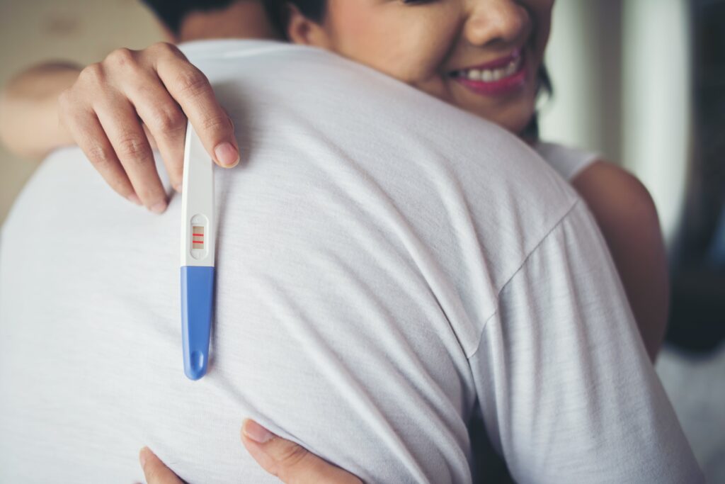 happy-couple-smiling-after-find-out-positive-pregnancy-test-bedroom